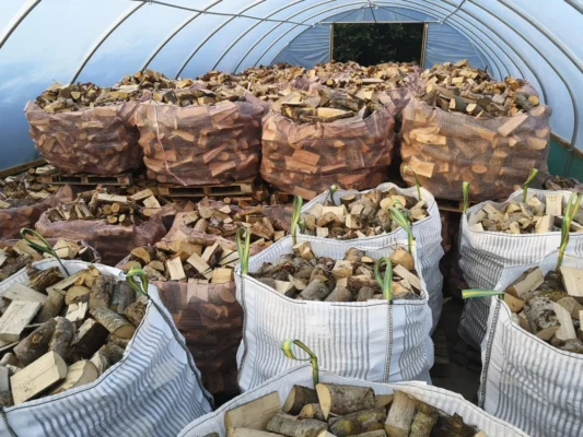 Bulk bags and net bags of firewood stored inside a polytunnel